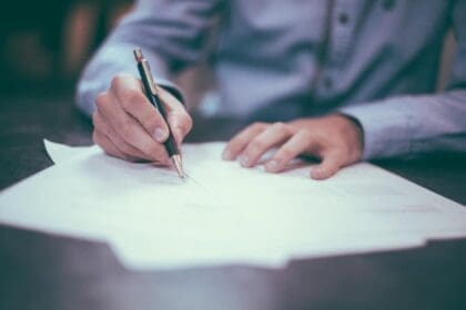 Pair of hands holding a pen and signing a contract.