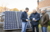 Installers standing by a solar panel.