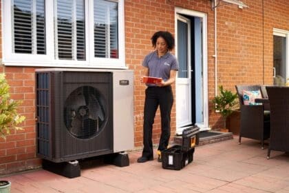 A woman looks at a heat pump outside a building.