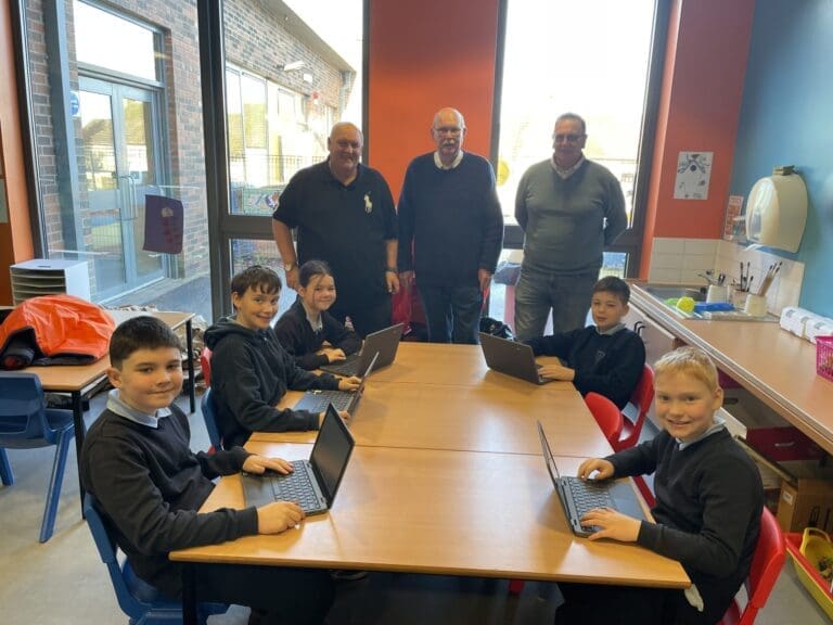 Children sitting at desks with new laptops