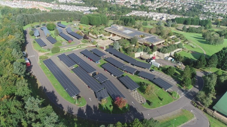 An aerial view of a car park with lots of solar car ports on it.