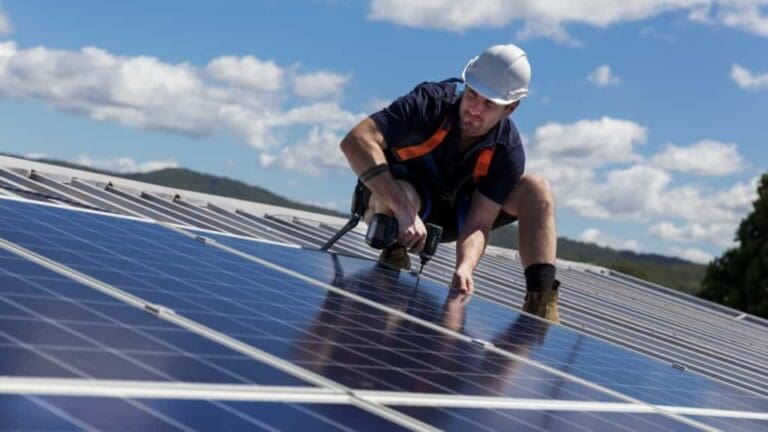 A man using a tool to fit a solar panel on a commercial rooftop.