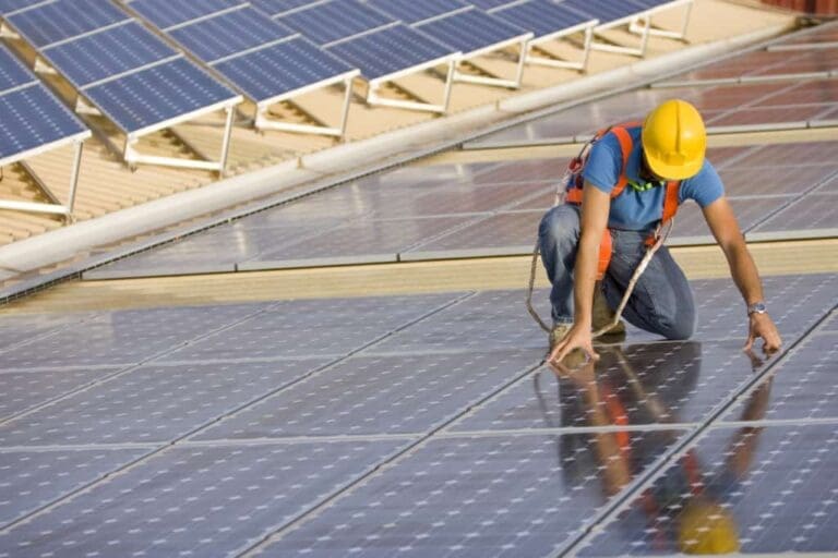 A picture of an installer on a roof full of solar panels.