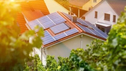 A domestic roof covered in solar panels with the sun shining on it.