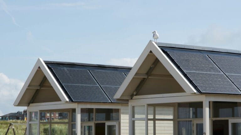 A picture of two domestic roofs with solar panels on them.